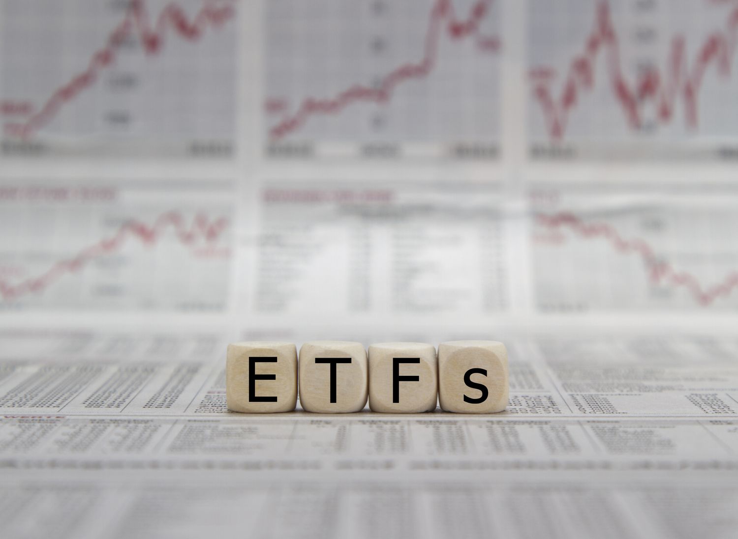 ETF exchange trades funds word on a blurred business newspaper.