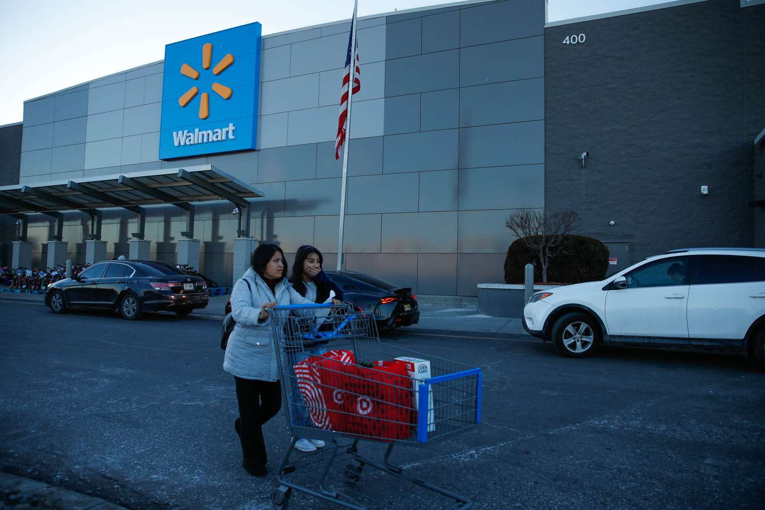 Two shoppers push a Target shopping cart past a Walmart storefront.