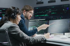 Two traders looking at market activity on computer screens