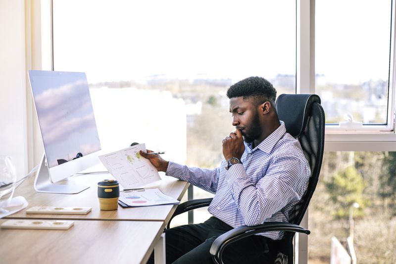 A man at a computer is pondering.