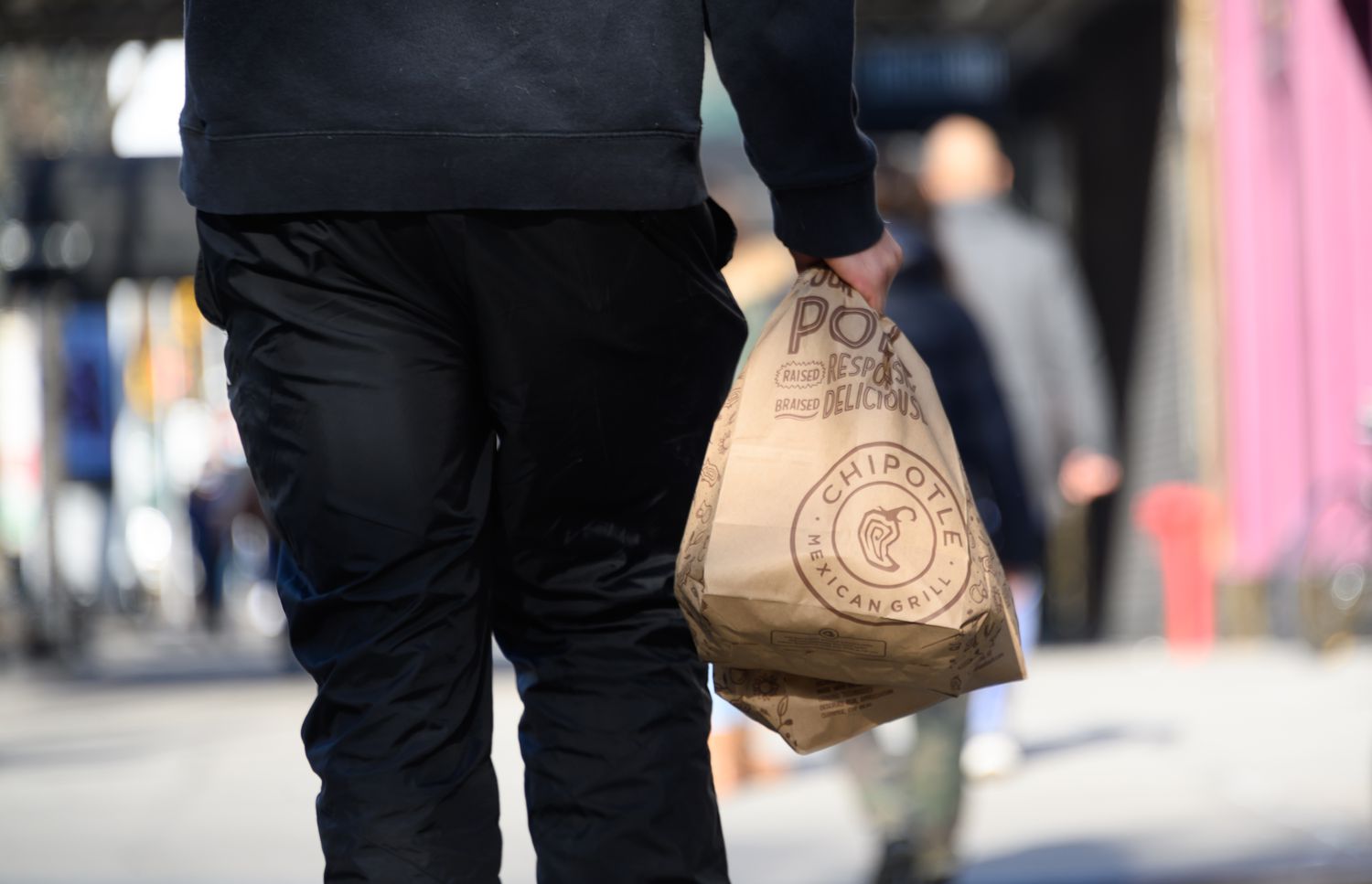 A person carries Chipotle bags in New York City. 