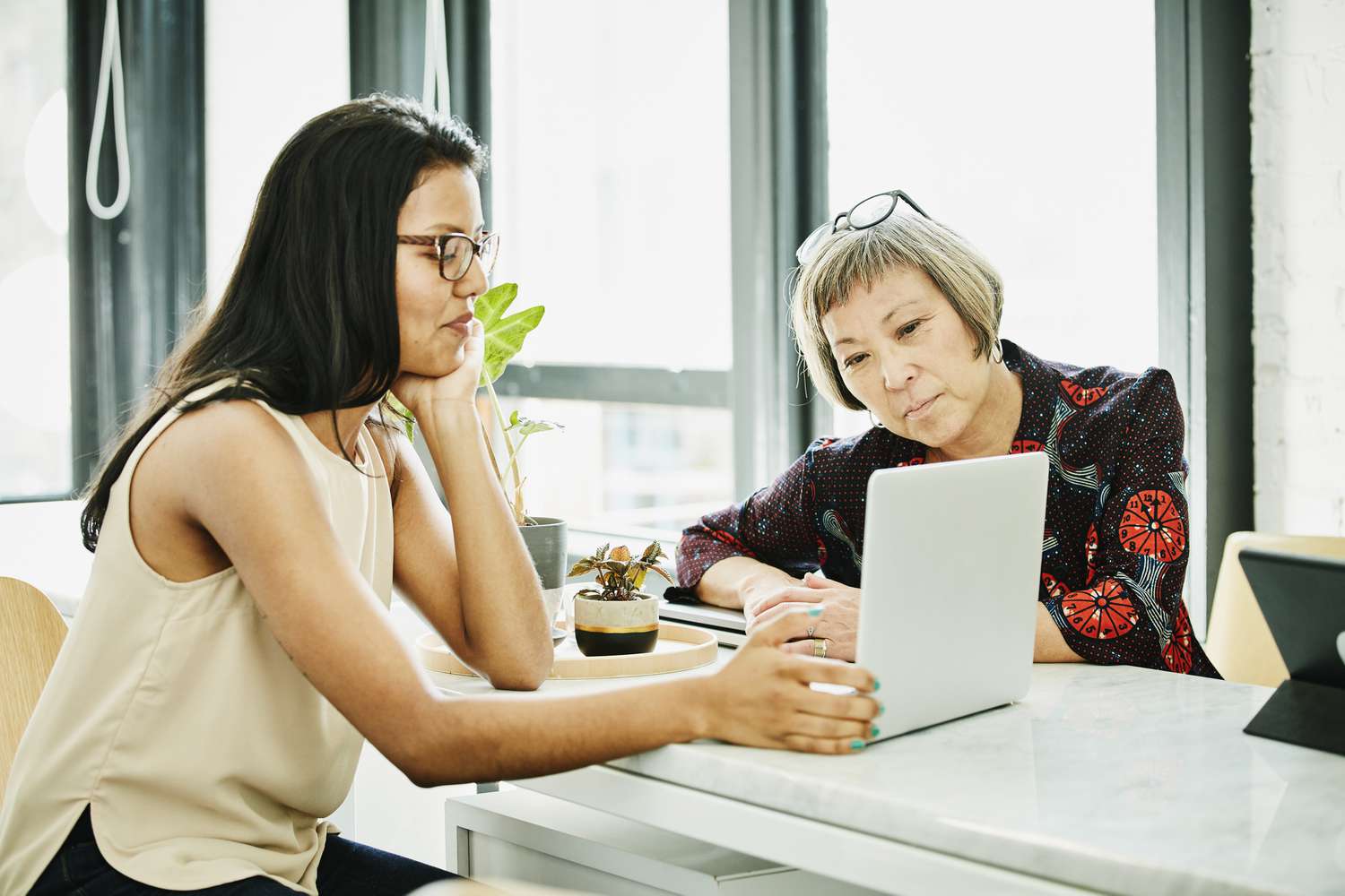 Female financial advisor reviewing data on laptop while meeting with businesswoman in office