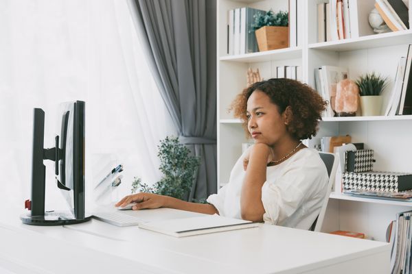 A woman sits at a desk working on a computer.