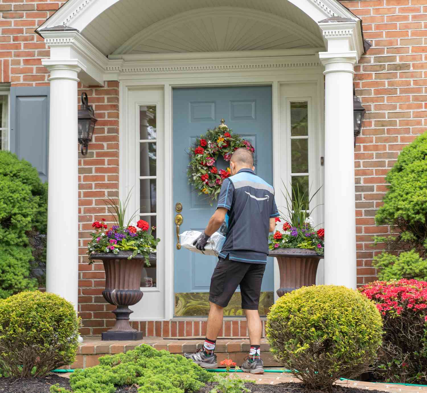 Amazon.com delivery person delivers a package to a front door