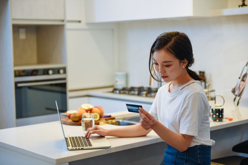 A student using a credit card home in front her computer.