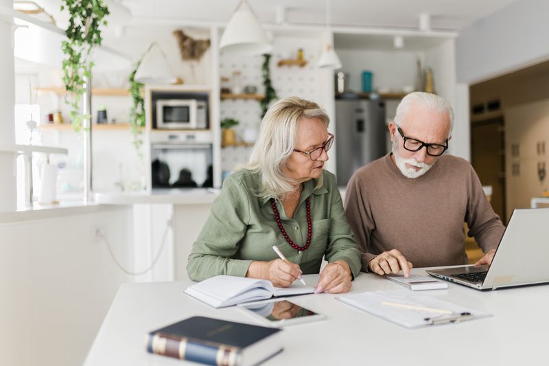 Older couple sitting in a white room planning their finances together.