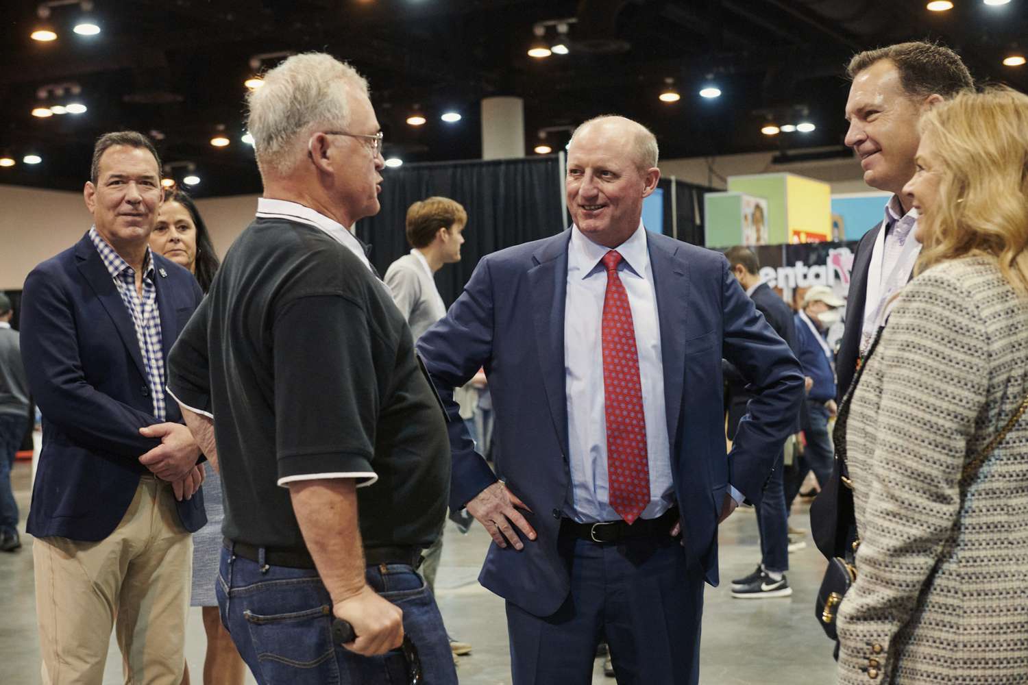 Greg Abel is pictured at the center of a group of people conversing in an indoor event space