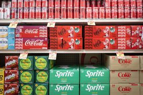 A variety of Coca-Cola products are seen on a grocery store shelf.