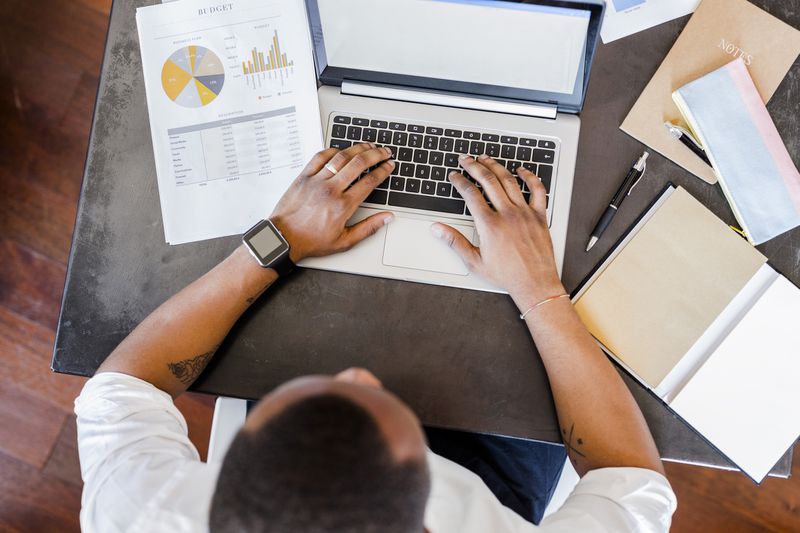 Man using laptop at desk in home office.