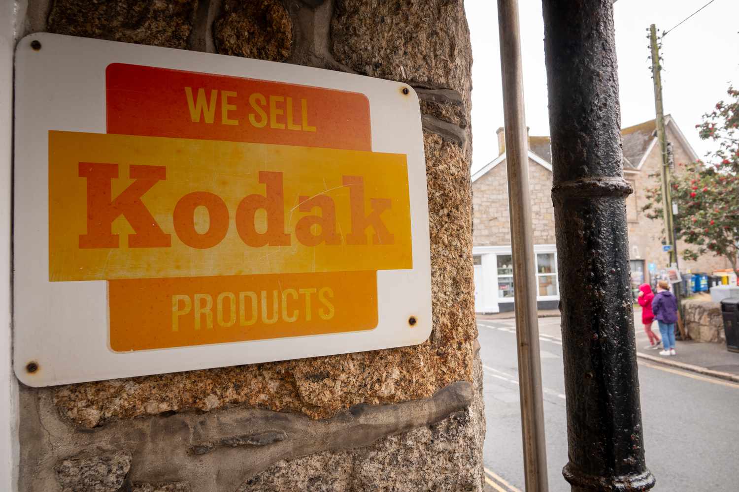 A old metal shop sign displays Kodak advertises products outside a pharmacy in Newlyn Harbour near Penzance on August 25, 2023 in Cornwall, England. 
