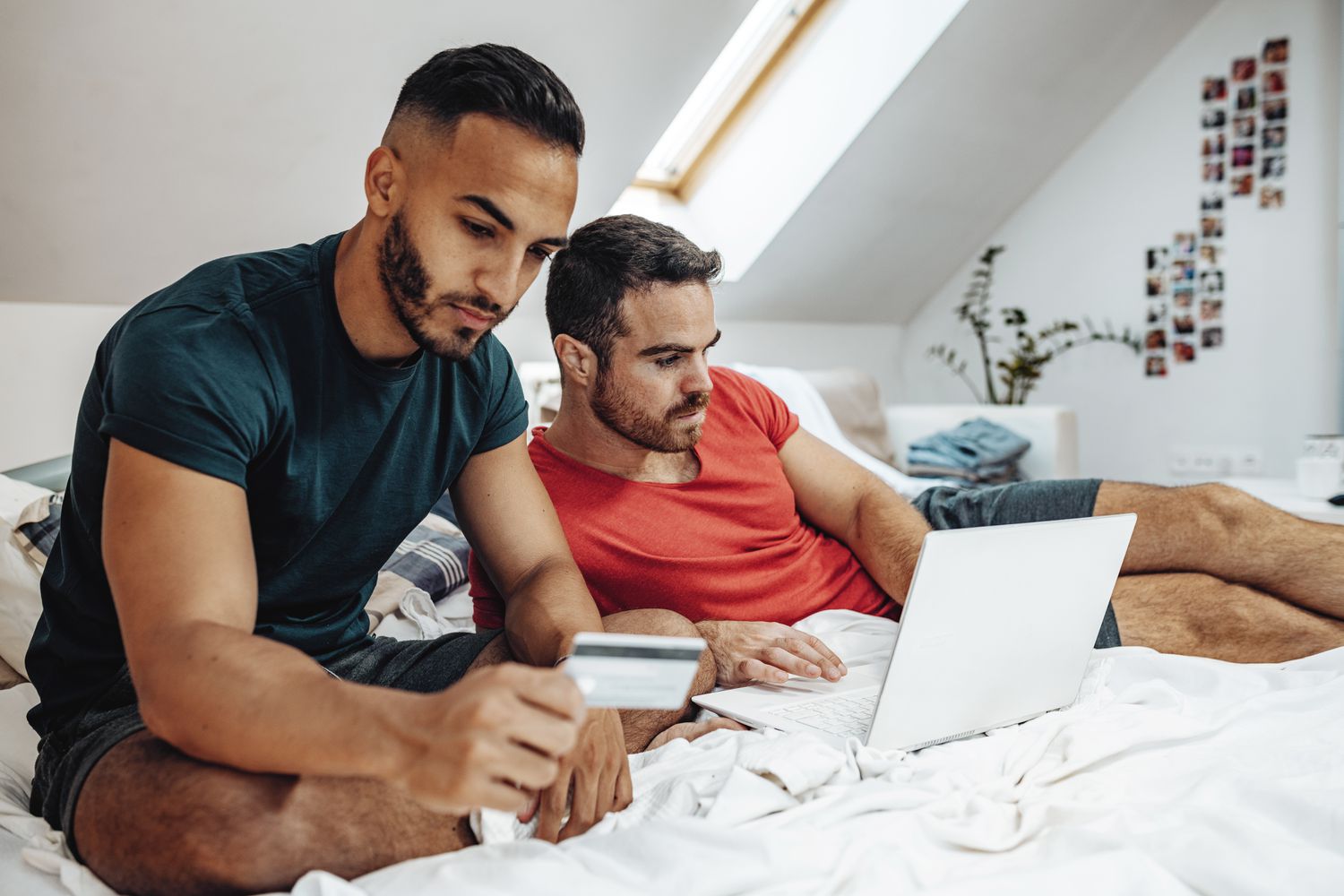 People sitting on their bed at home doing credit card balance transfer for a lower interest rate.