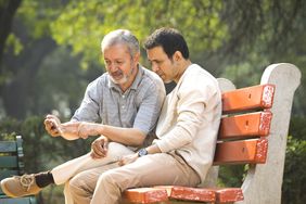 An older man and a younger man sit on a bench.