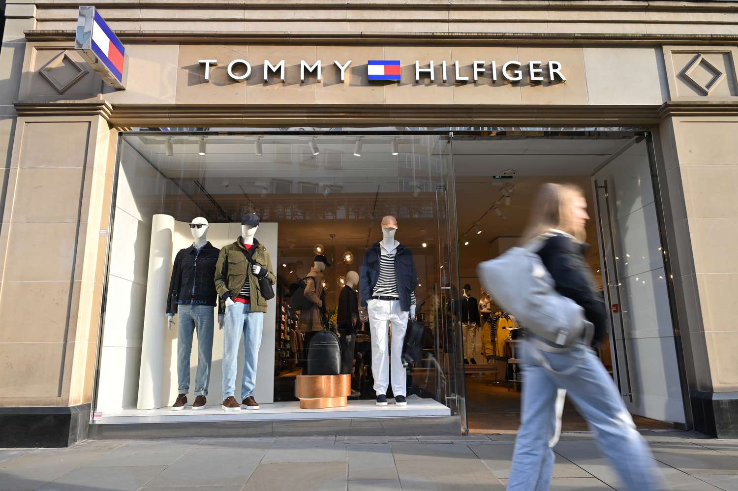 People walk past a Tommy Hilfiger luxury fashion label store in London