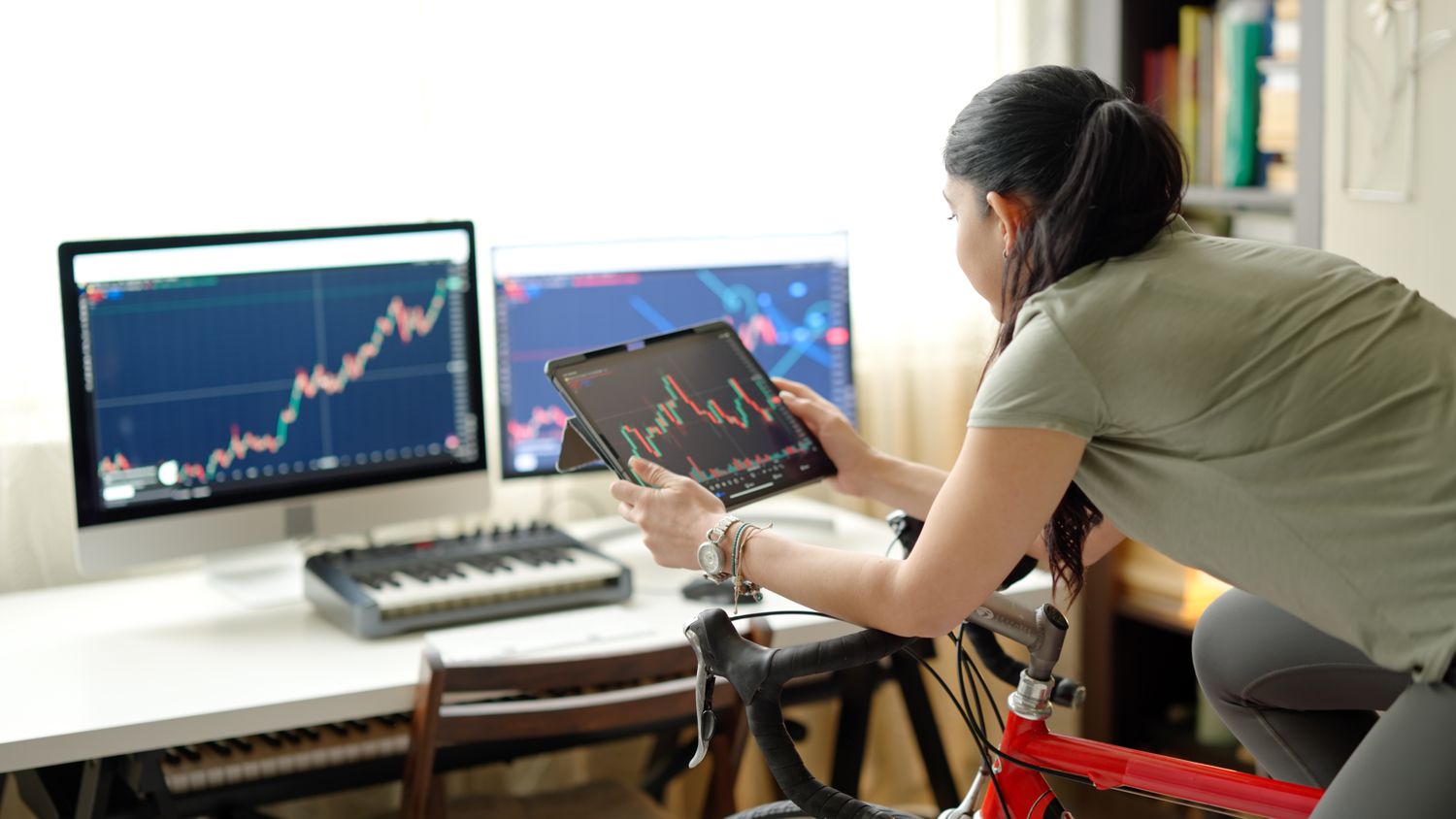 Woman on a stationary bike looking at charts on several screens.