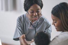 A mother holds her newborn baby at a routine medical checkup.