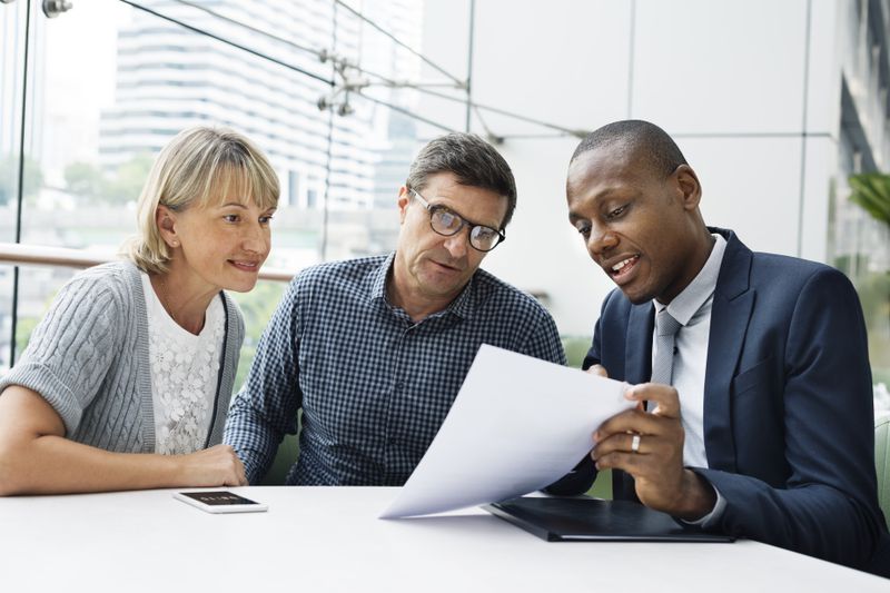 Financial advisor looking over paperwork with a middle-aged couple.