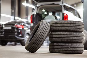 Stack of tires in front of cars.