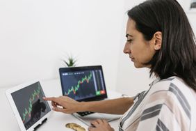 Woman checking market data on two computer screens