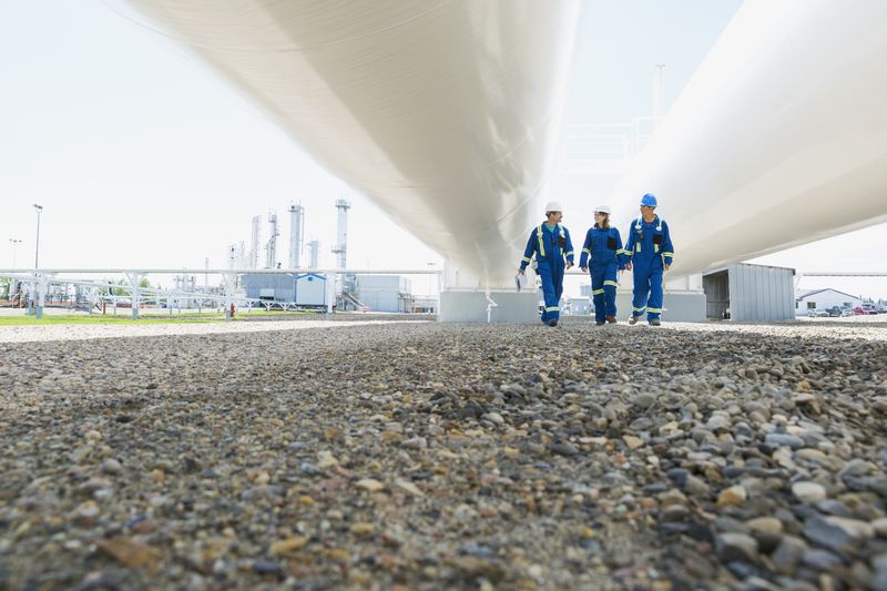 Workers walking below tanks at gas plant