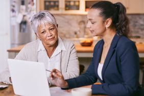 An older adult works with a lawyer as they discuss their last will and testament.