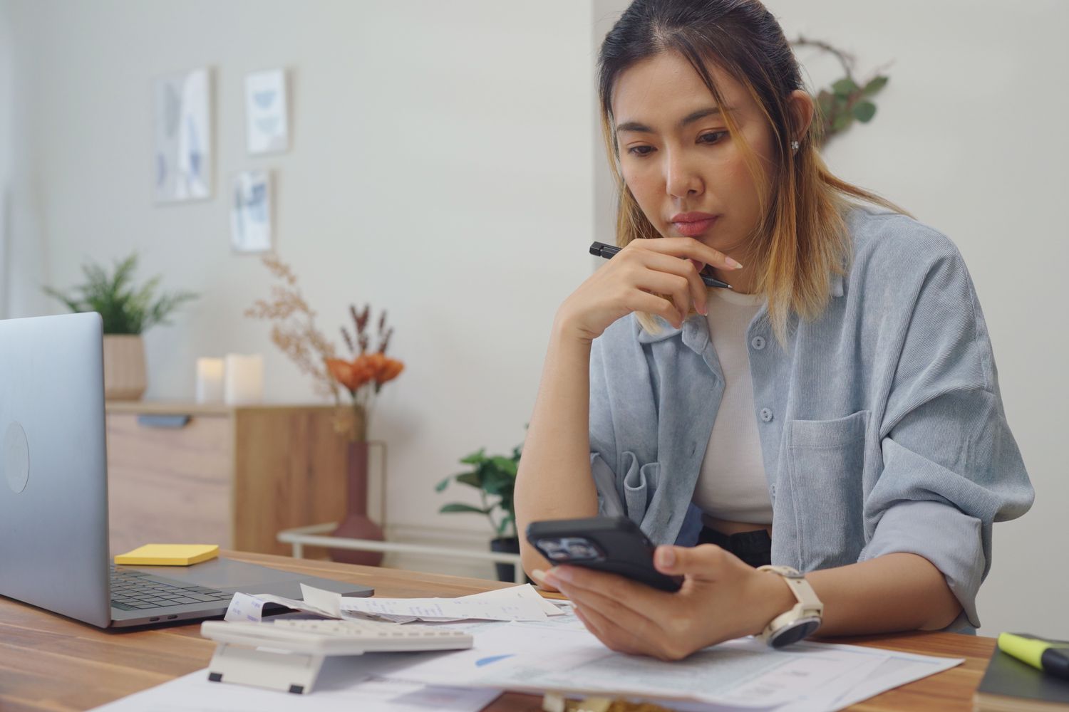 Woman looking at smartphone, thinking about the taxes she has in front of her.