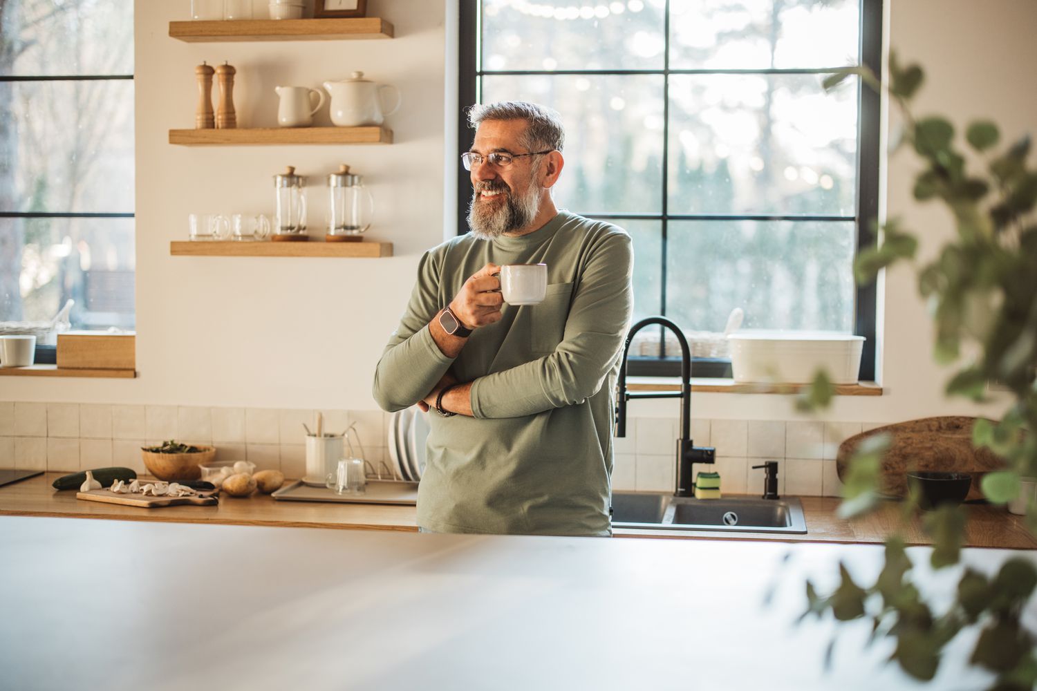 A n investor standing alone in kitchen, drinking coffee and enjoying in his morning routine.