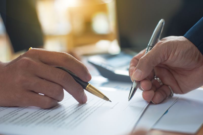 Close up of people signing contract for treaty reinsurance.