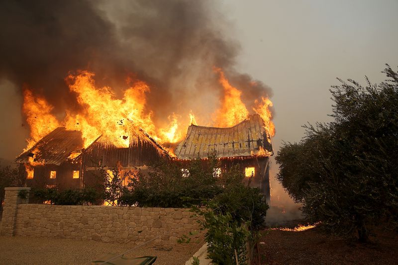 Raging fire overtaking barn sends dark smoke into the sky and causes the roof to collapse
