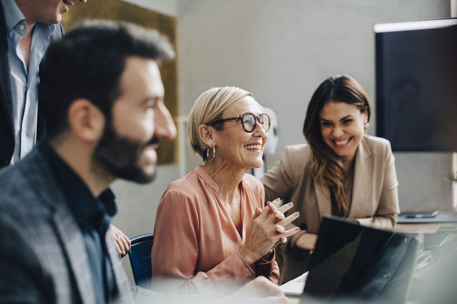 Three employees convene in a conference room.
