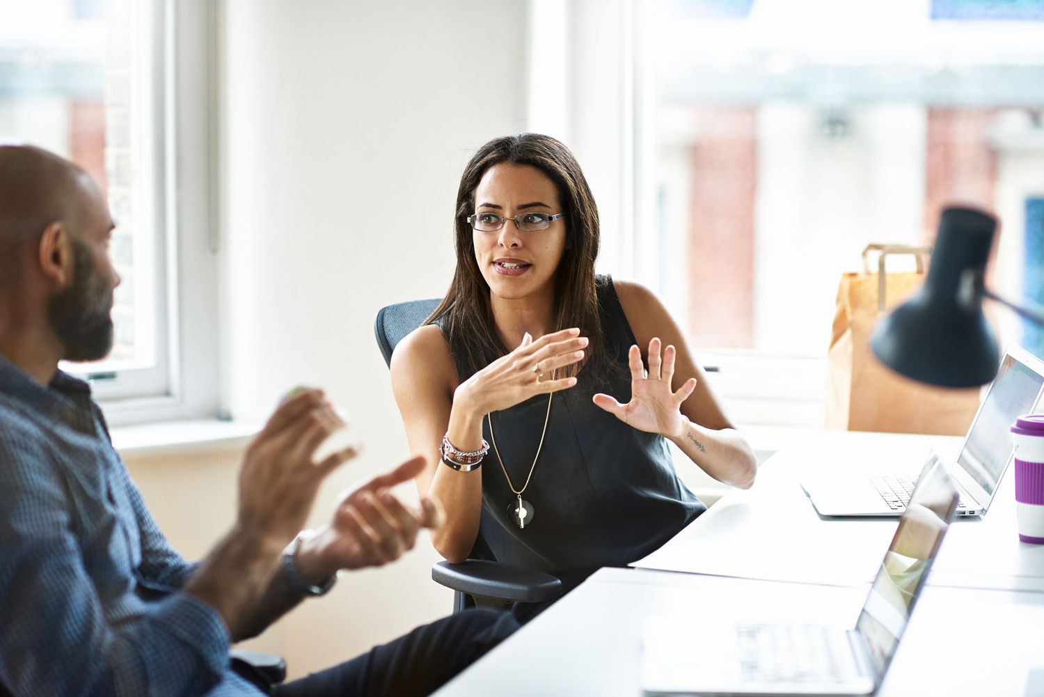 Two people seated at an office table, talking