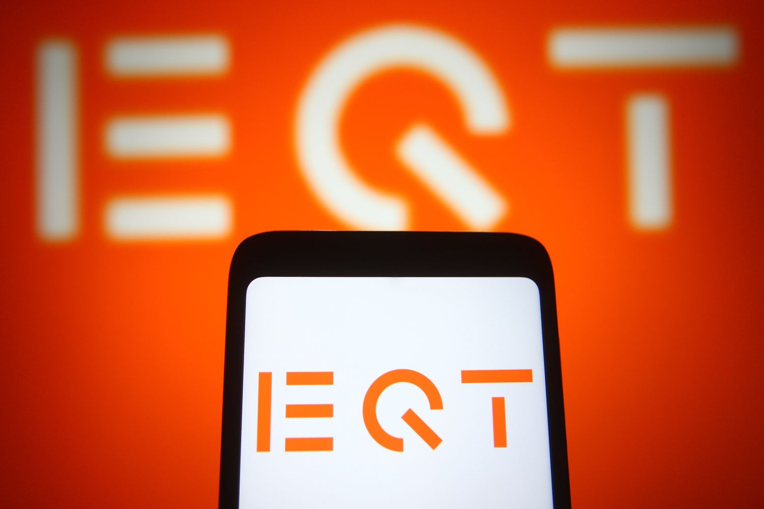 An EQT Partners AB logo is seen on a smartphone and a screen
