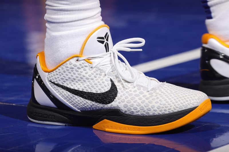 A white, black, and yellow Nike shoe is seen on a basketball court.