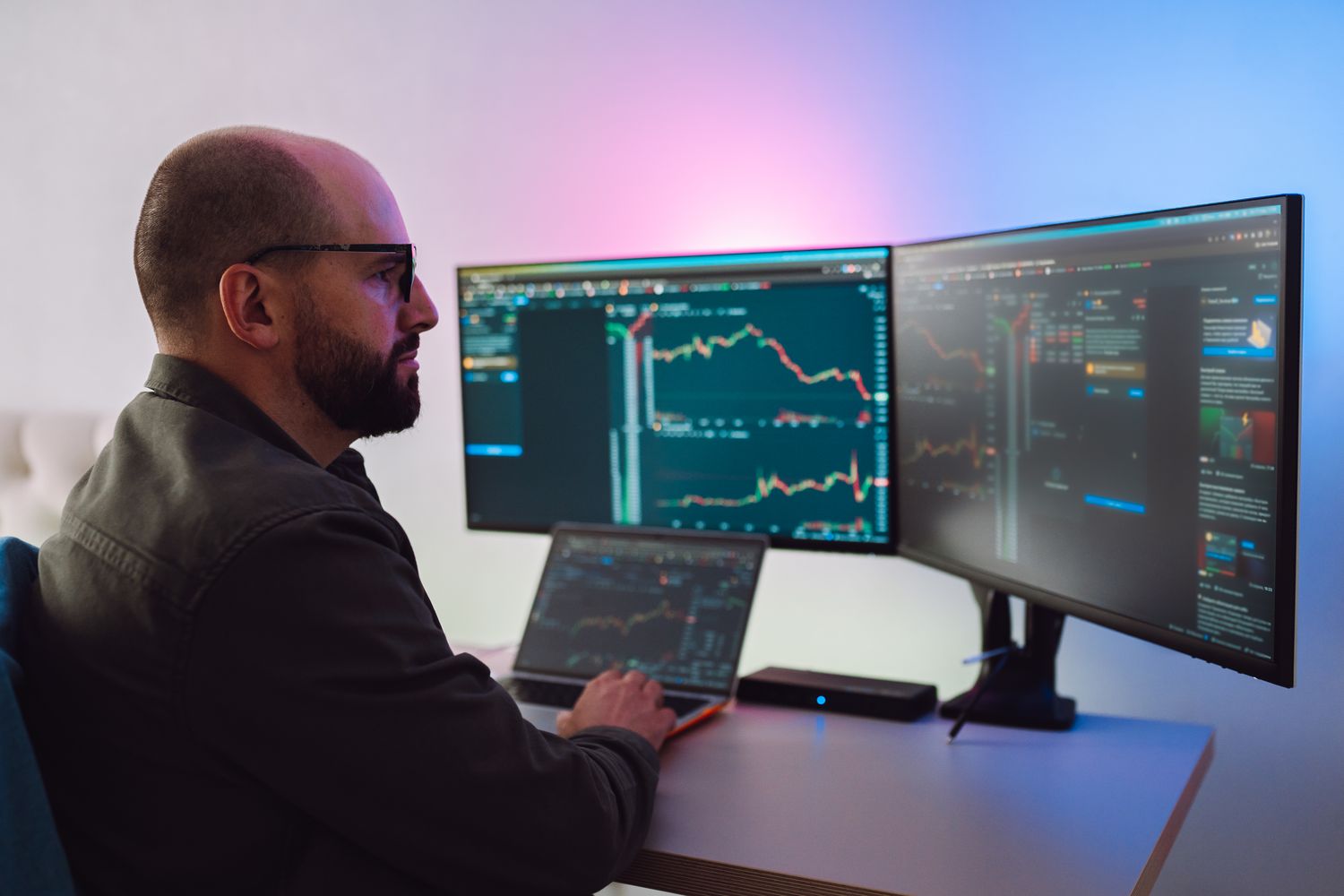 Day trader working at home in front of multiple screens to quickly profit from short-term market trends.