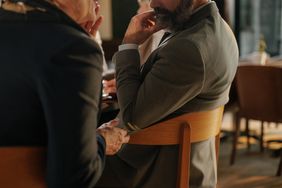 Two business people talk quietly during a dinner meeting and trade insider company information.