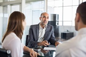 Financial agent showing new investment to young couple.