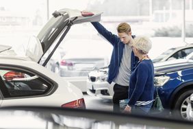Mother and son examining new car in dealership