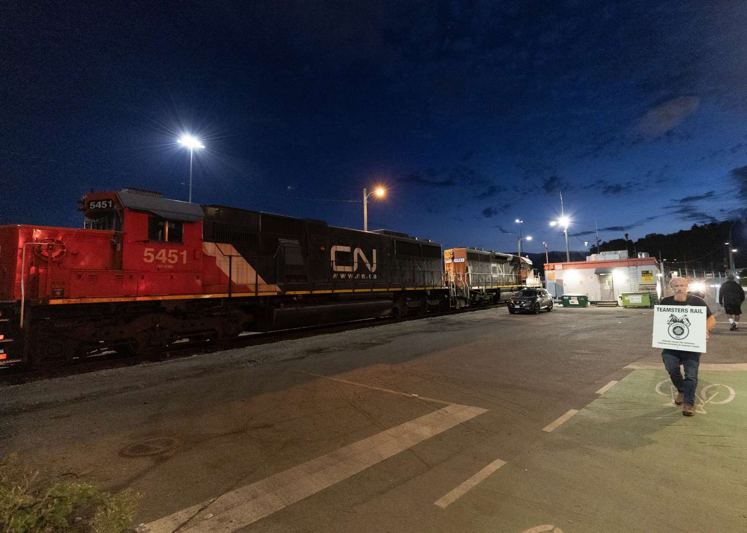 A Teamsters union member walks the picket line at the entrance of CN Rail Lynn Creek Yard on August 21, 2024 in North Vancouver, British Columbia,