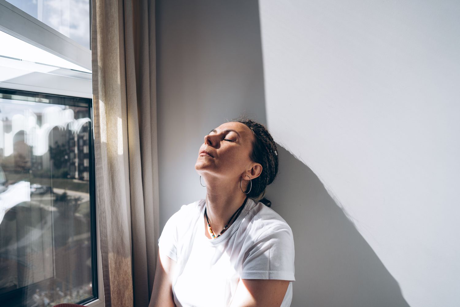 Woman looking stressed sitting against a wall.