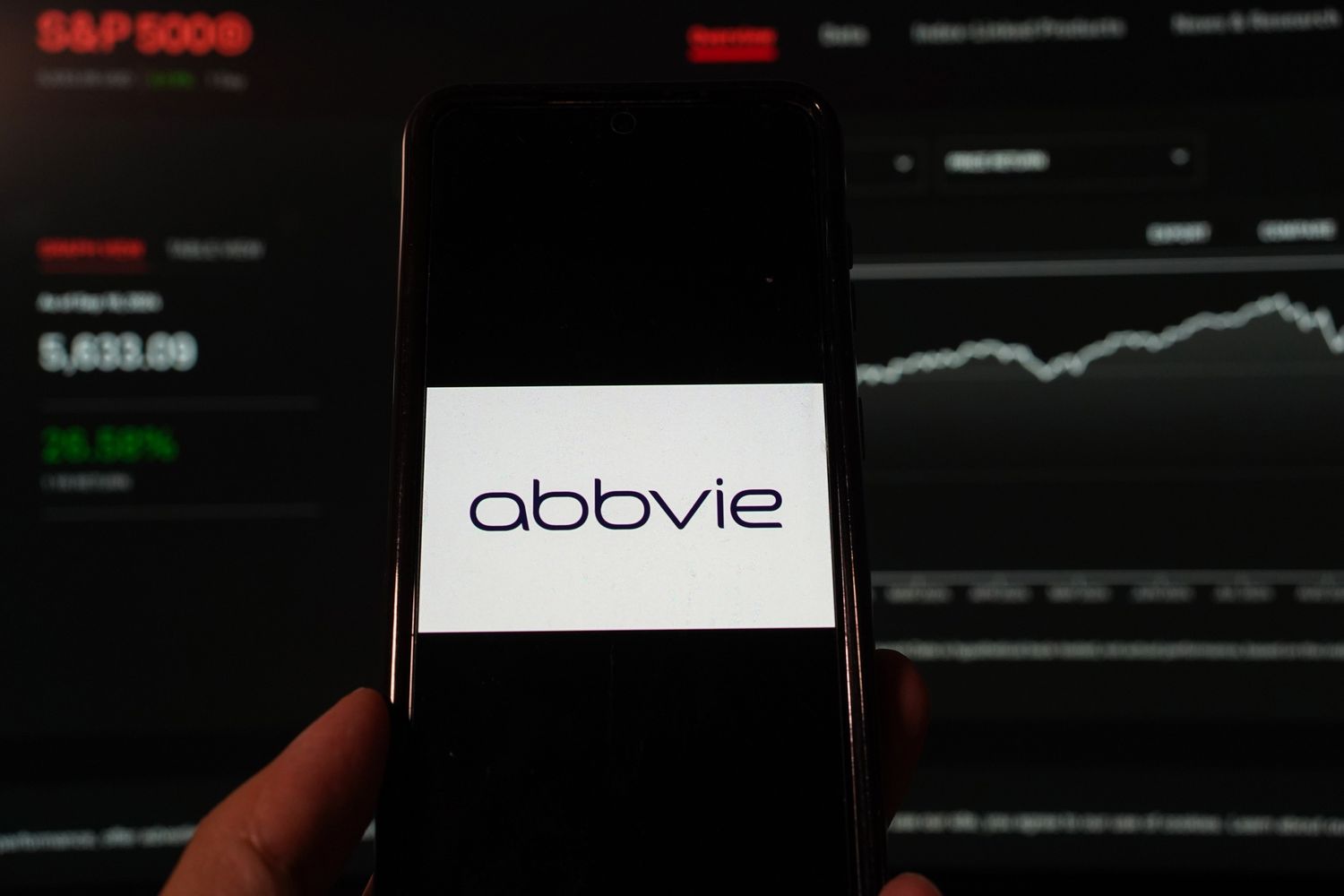 AbbVie Inc. logo is displayed on a smartphone with a S&P index website background