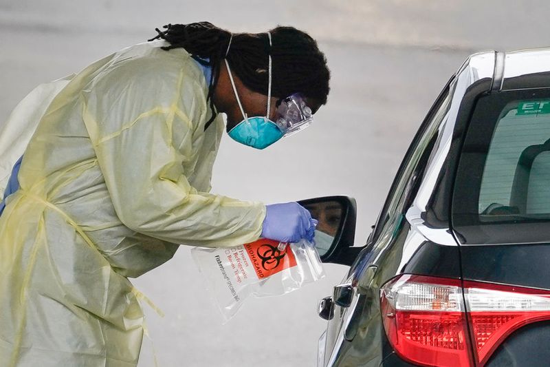 A healthcare worker screens a patient for COVID-19 at a drive through coronavirus testing site.