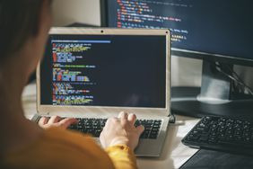 A close of a woman working on a program on a laptop at her home office.