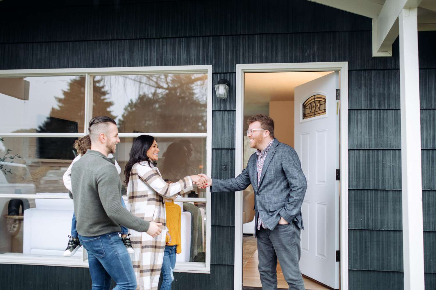 A real estate agent meets a family in front of a house
