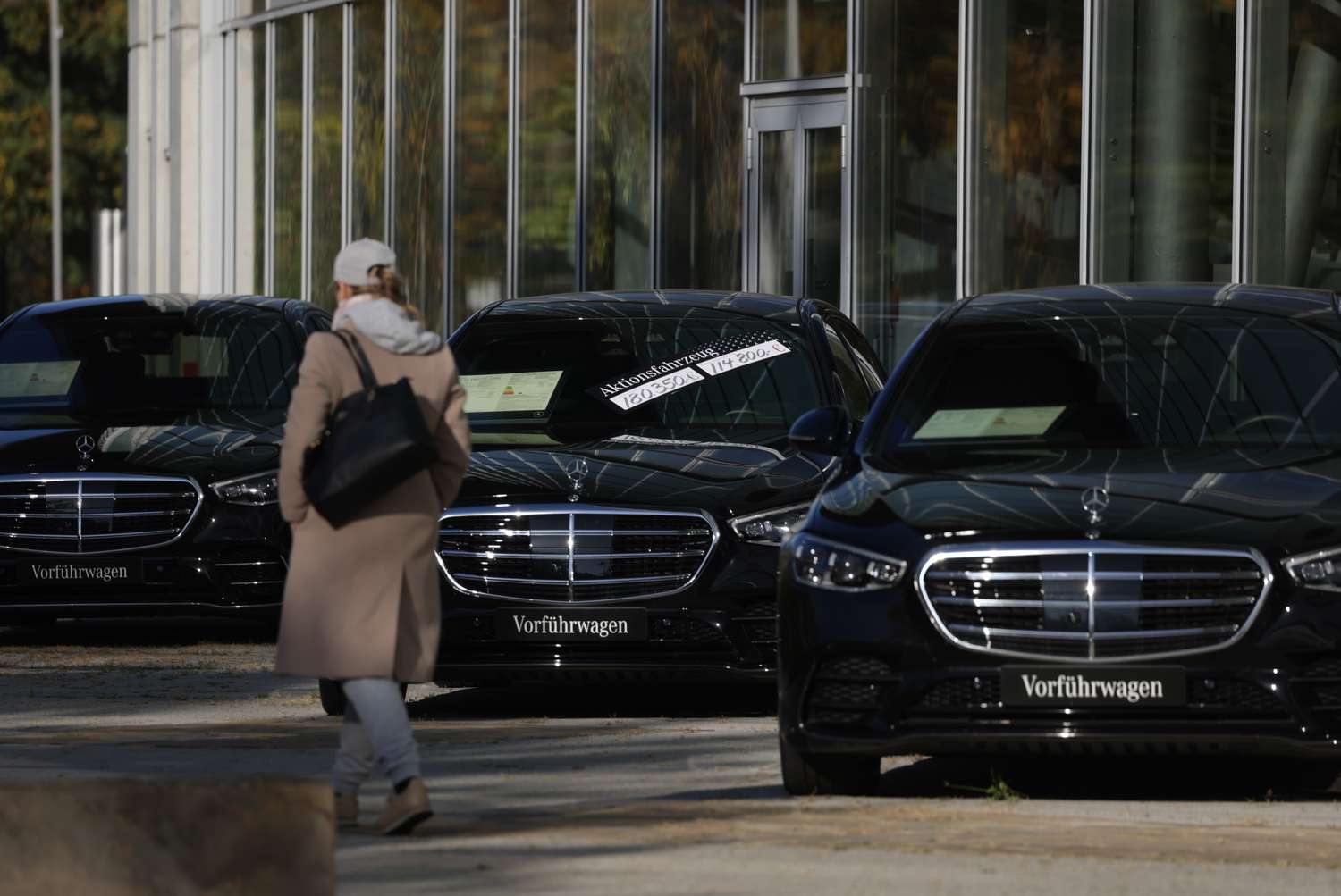 A woman walks past Mercedes-Benz cars on display at a Mercedes-Benz dealership