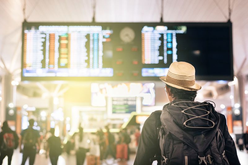 Man Looking at Illuminated Arrival Departure Board