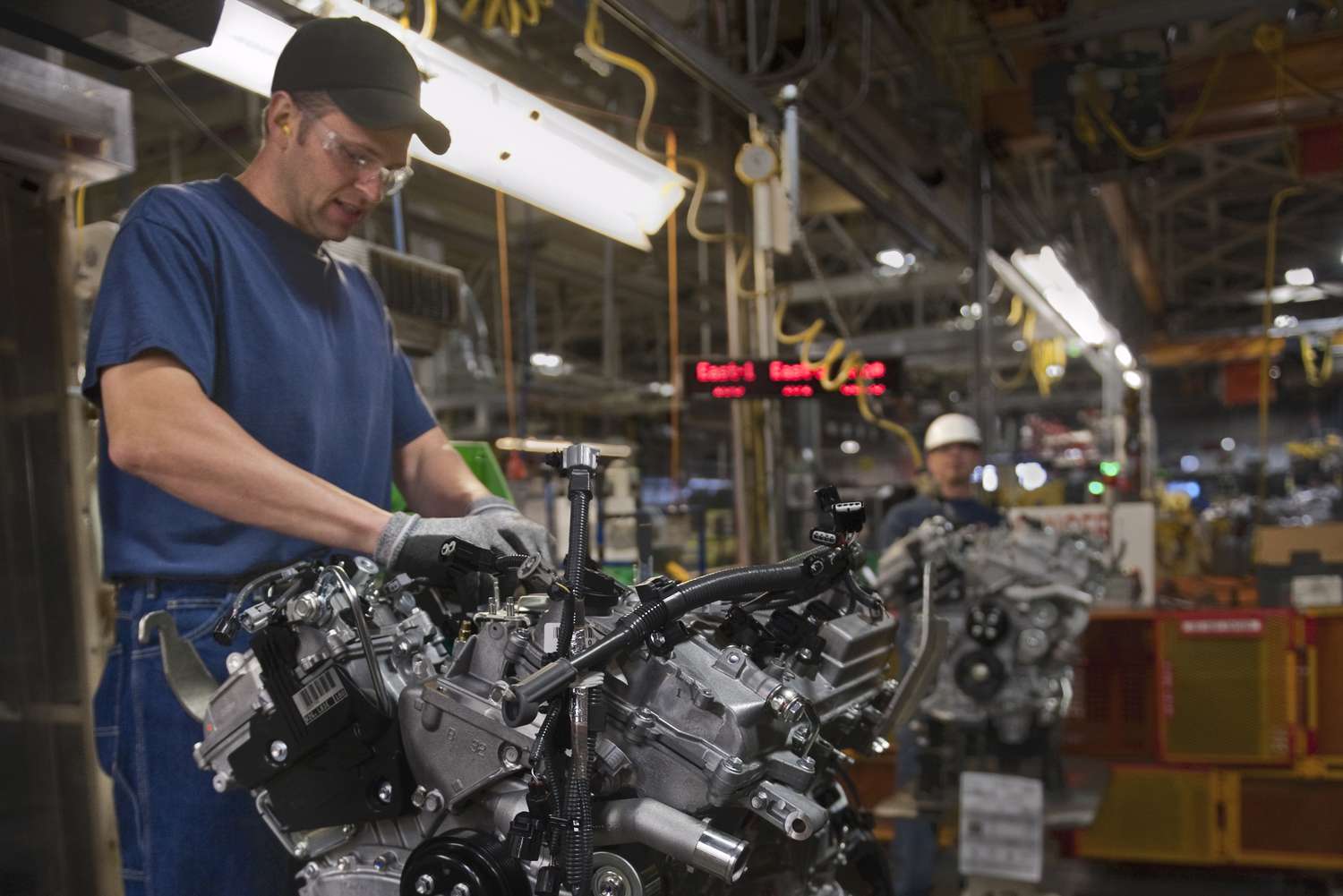 An auto worker assembles an engine in a factory