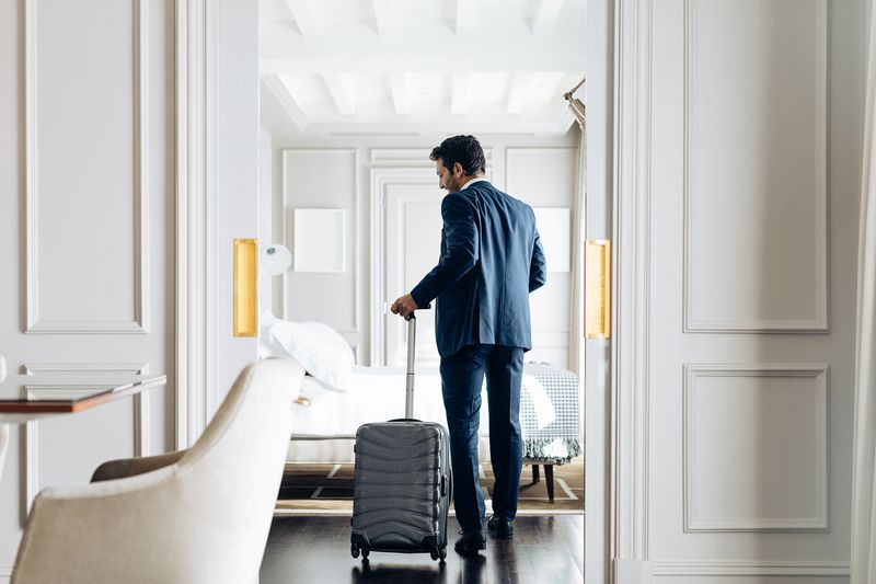 Businessman with Wheeled Luggage in Suite