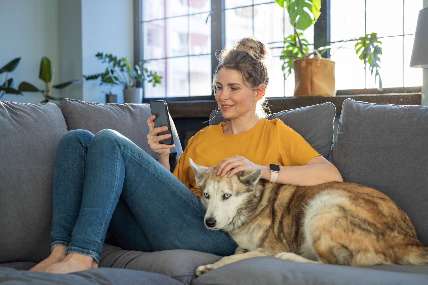 A woman on a couch uses a phone.