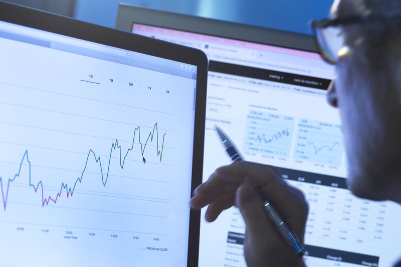 A stock analyst researching share price data of a company on the computer.