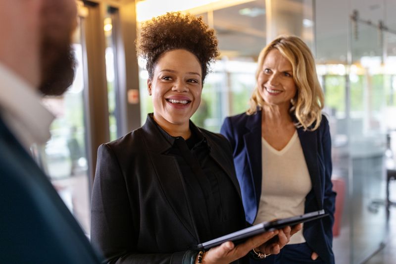 Three co-workers have a discussion in a corporate setting