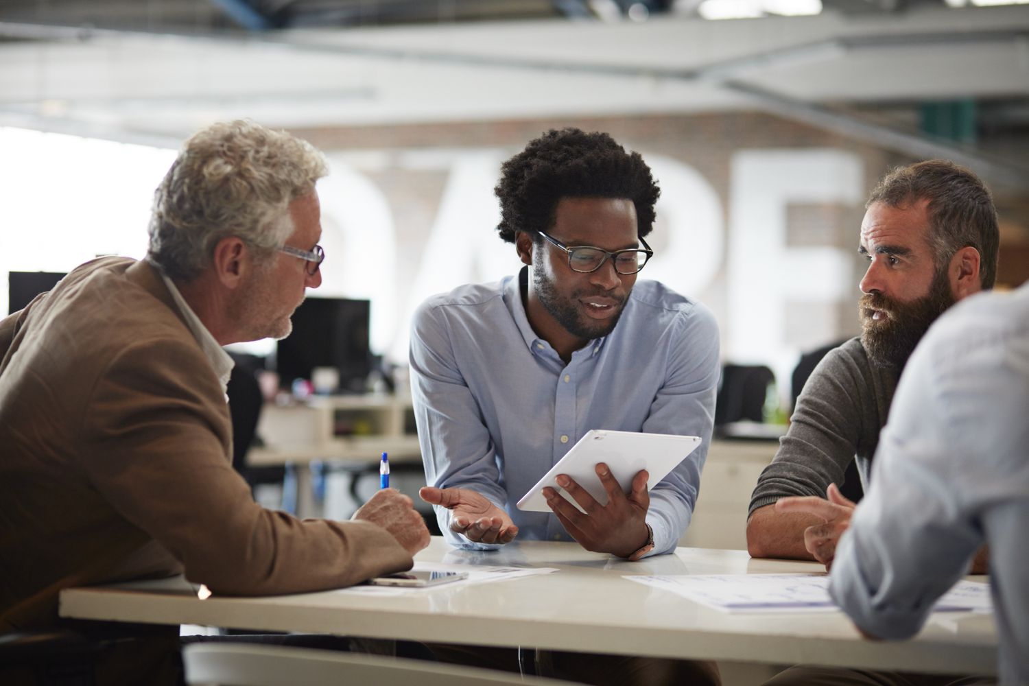 Stockbrokers meet around a countertop in an office as they discuss a large short sell order that will require a stock loan.